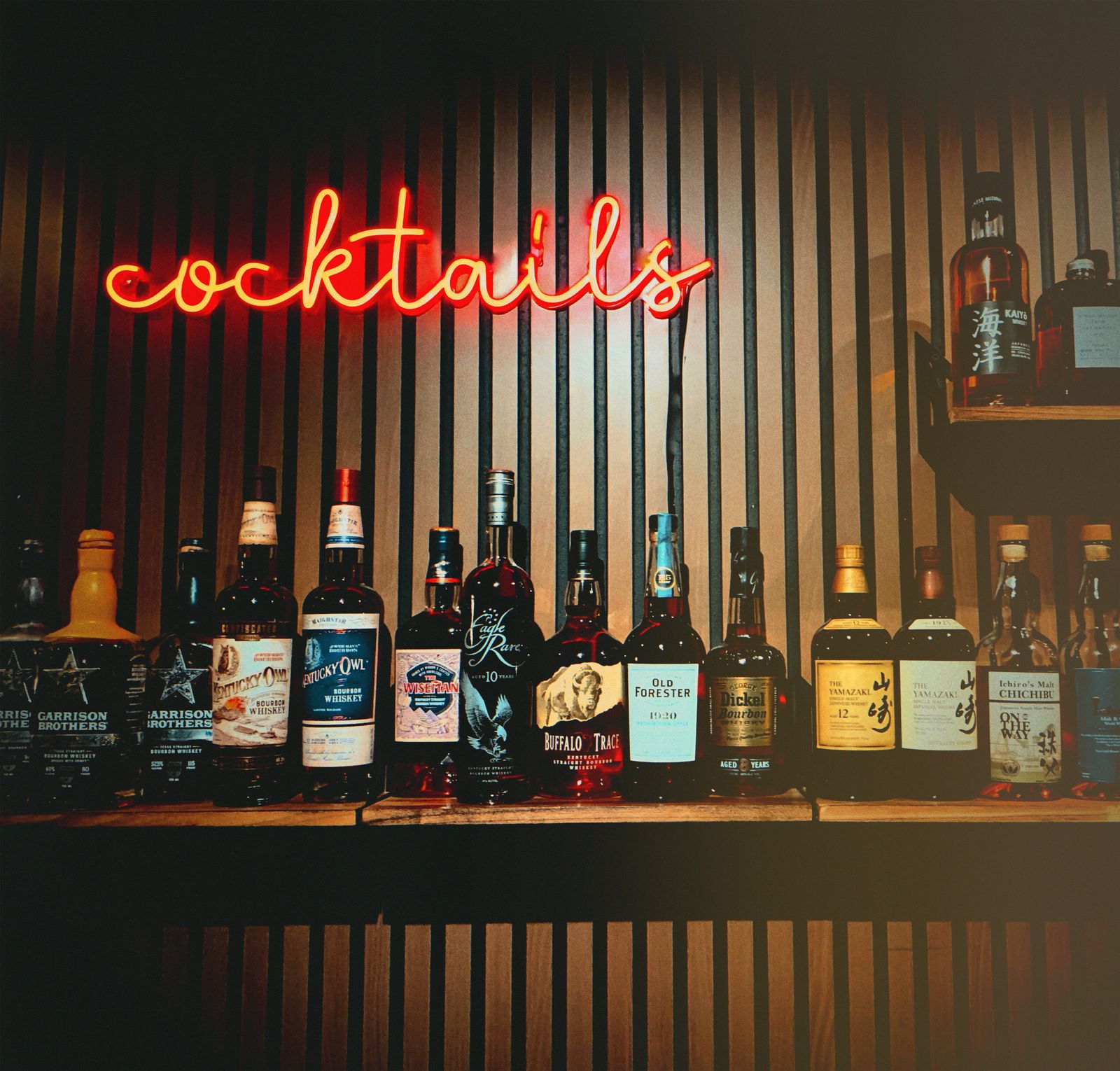 The neon cocktails sign glowing above Lucky Duck's curated whiskey collection