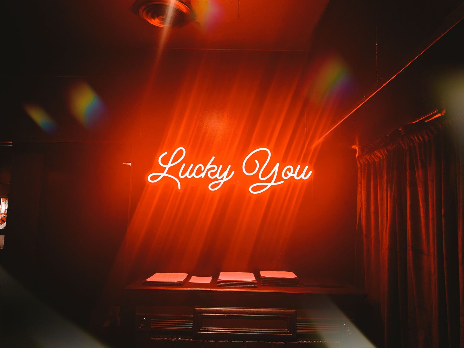 The Lucky You neon sign glowing red above Lucky Duck's dining room